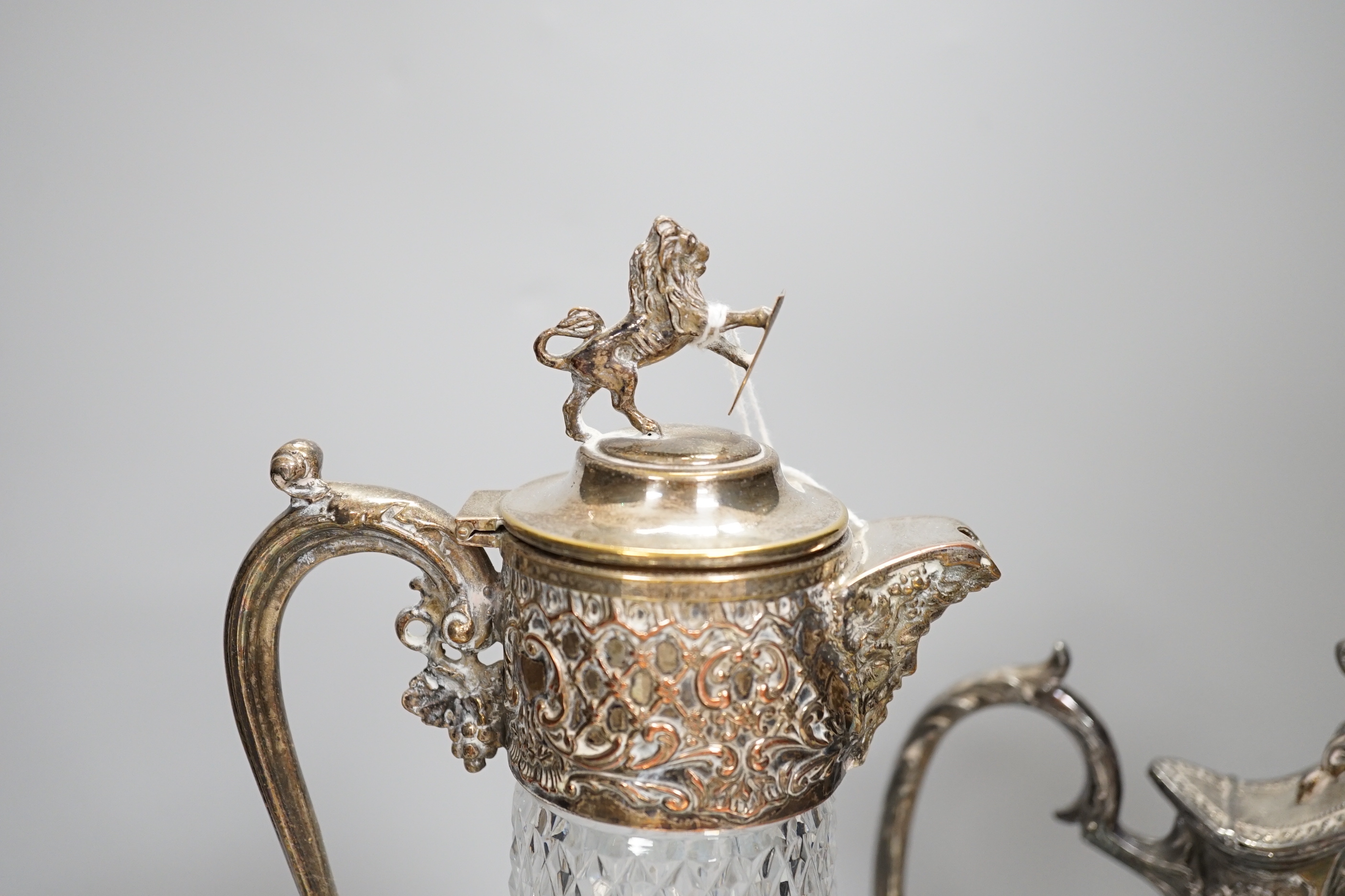 Two claret jugs, one with gilt decoration, four silver plated cup holders with glass liners and silver plated fish servers, the largest 32cm high